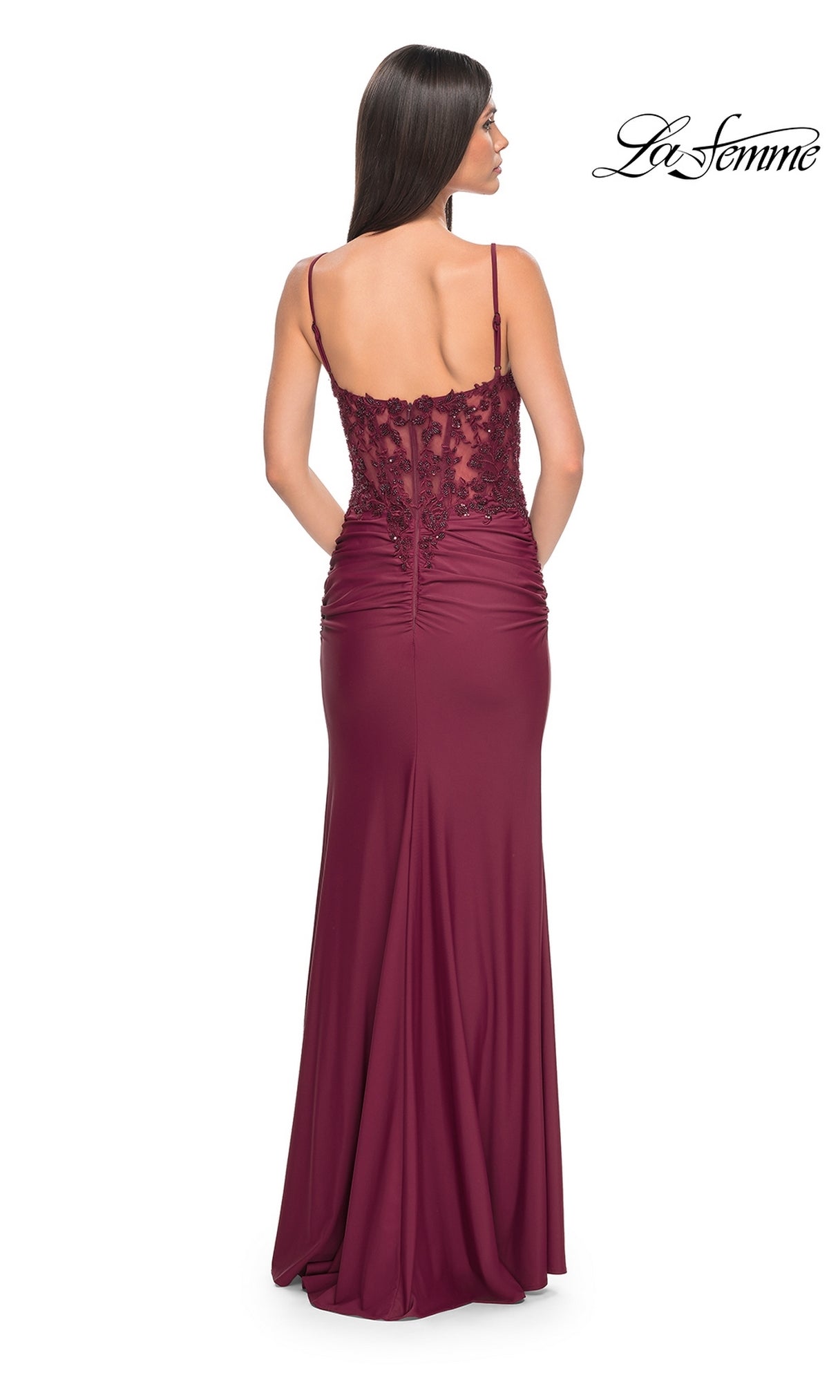 Woman wearing the La Femme Plunging V-Neck Long Prom Dress 32132, a sleeveless burgundy gown with a lace corset bodice, bead accents, ruched sides, and a flowing floor-length skirt, elegantly shown from the back.